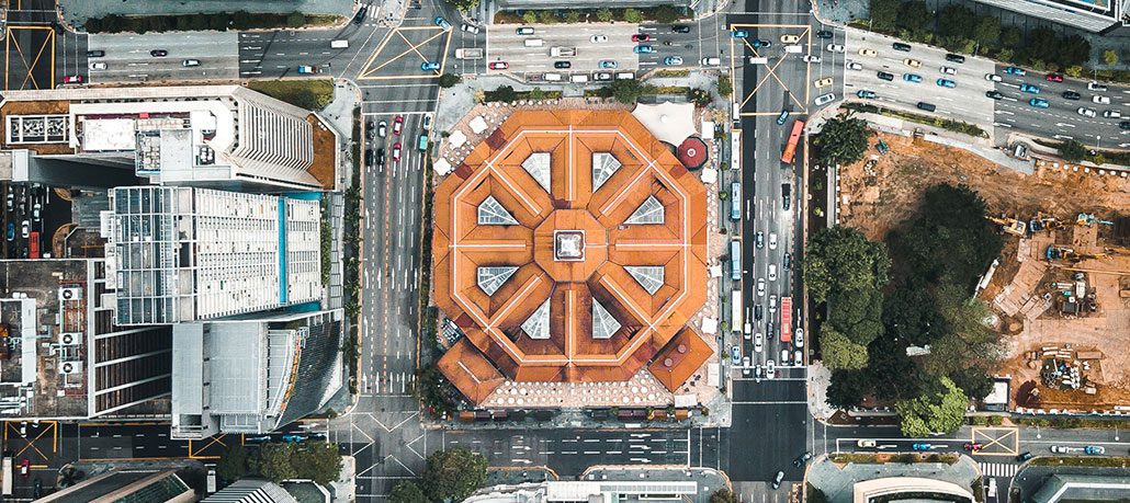 Aerial view of a building with a circular shape, surrounded by other city buildings.