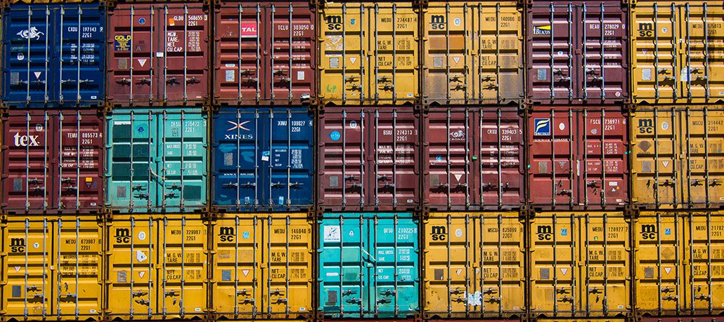 Close-up photo of three rows of colorful shipping containers stacked up