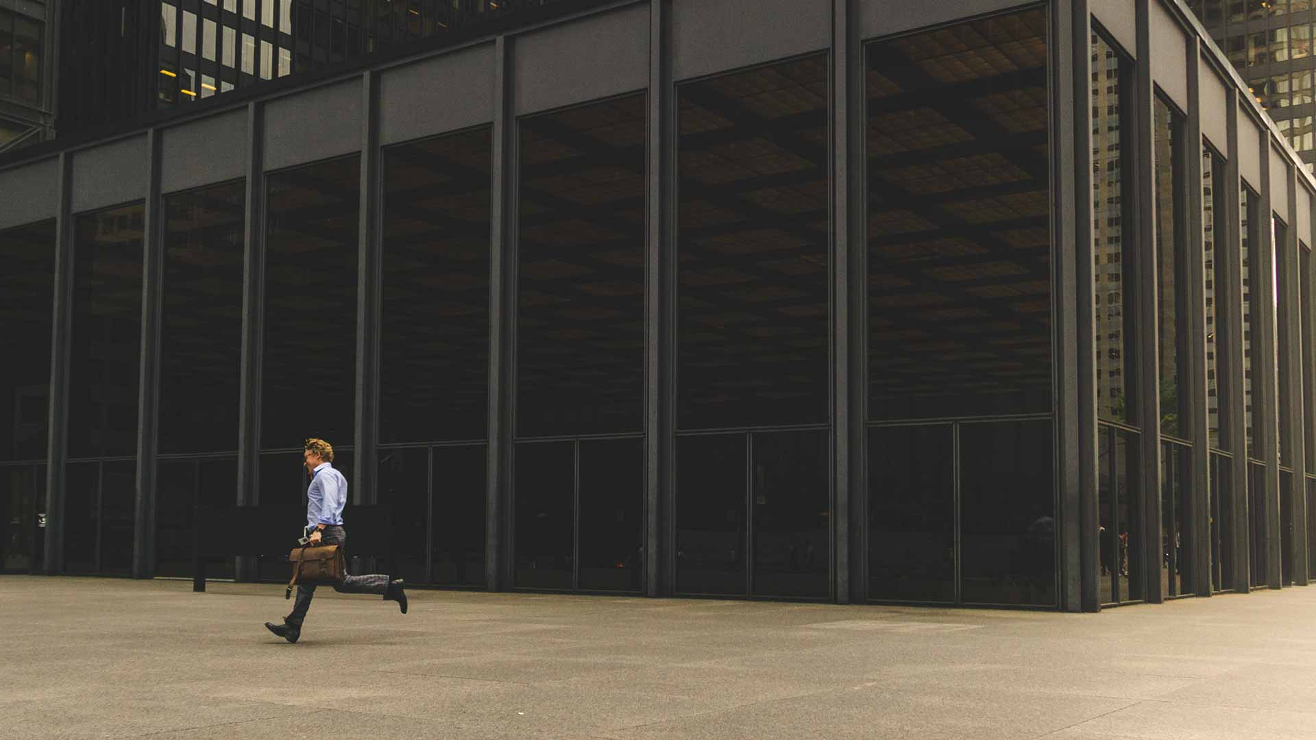 Rooms are lit inside a large glass office building on a city night